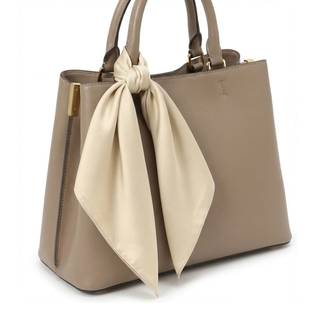 Foulard en satin beige noué sur un sac à main élégant, ajoutant une touche chic et féminine