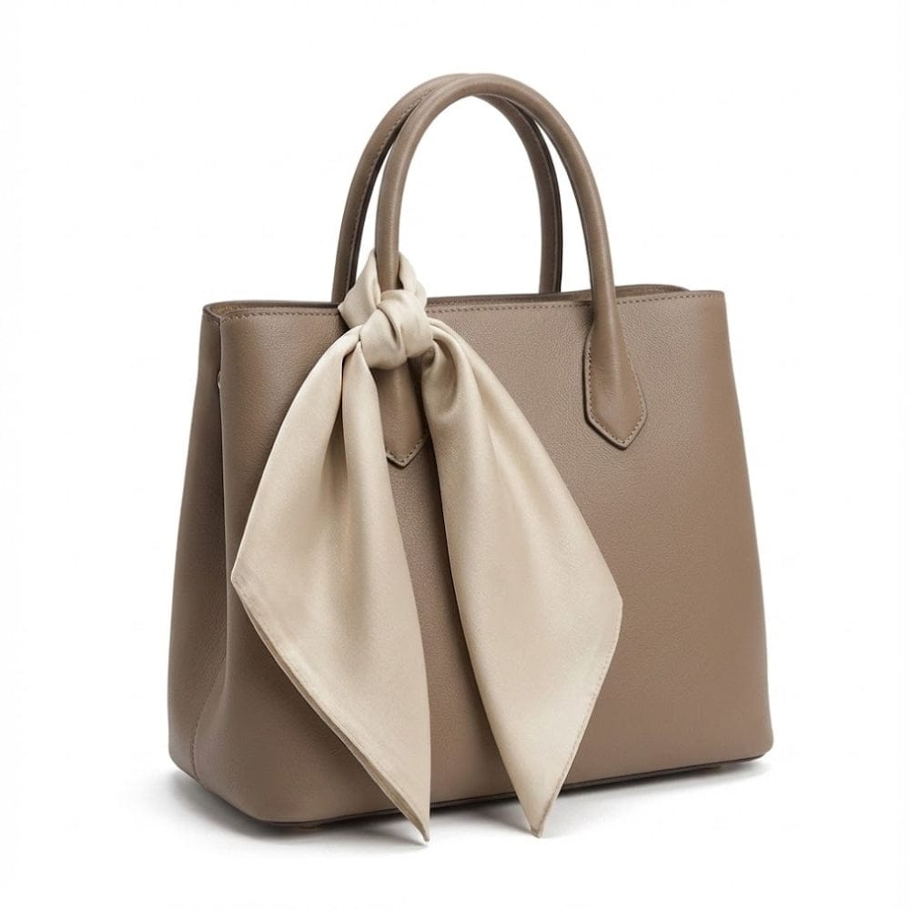 Foulard en satin beige noué sur un sac à main en cuir marron, ajoutant une touche d'élégance