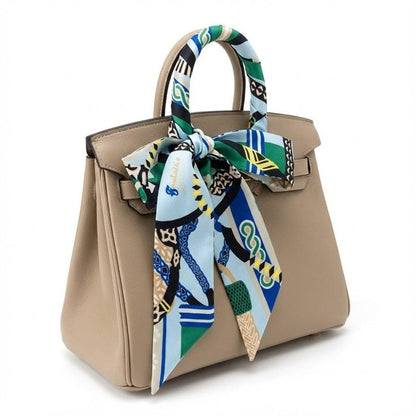 Foulard en soie aux motifs colorés, noué élégamment sur une poignée de sac à main beige