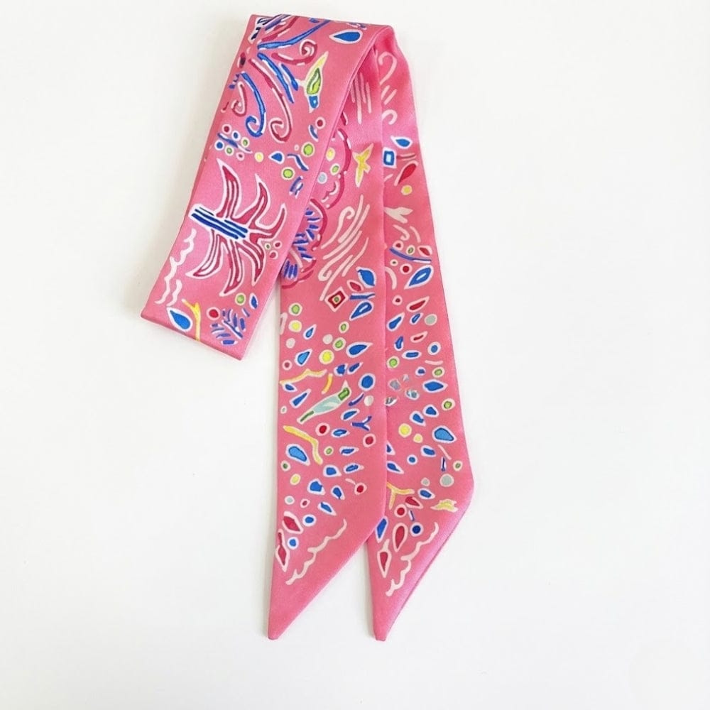 Foulard en satin rose avec motifs colorés, noué en bandeau, idéal comme accessoire chic pour cheveux