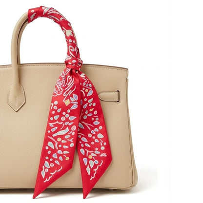 Foulard en satin rouge à motifs colorés, noué sur la anse d'un sac à main beige élégant