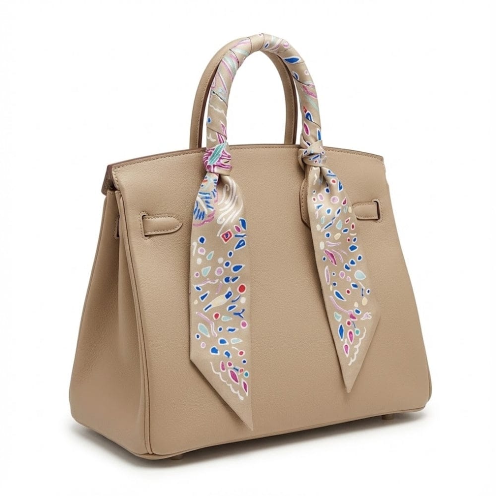 Foulard en satin aux motifs colorés noué sur un sac à main beige, ajoutant une touche chic et élégante