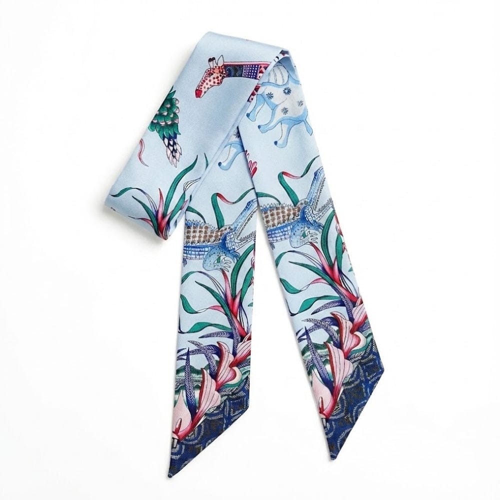 Foulard en satin bleu clair avec motifs animaliers et floraux, noué en bandeau élégant sur fond blanc