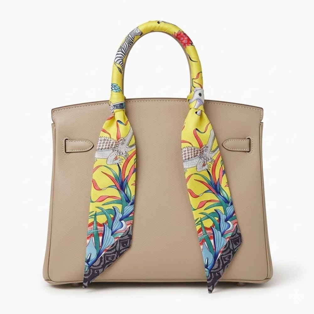 Foulard en soie jaune à motifs colorés noué sur un sac à main beige, ajoutant une touche d'élégance moderne