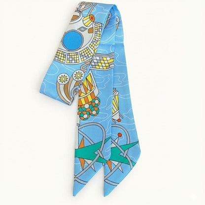 Foulard en satin bleu avec motifs graphiques colorés, noué élégamment sur un fond blanc