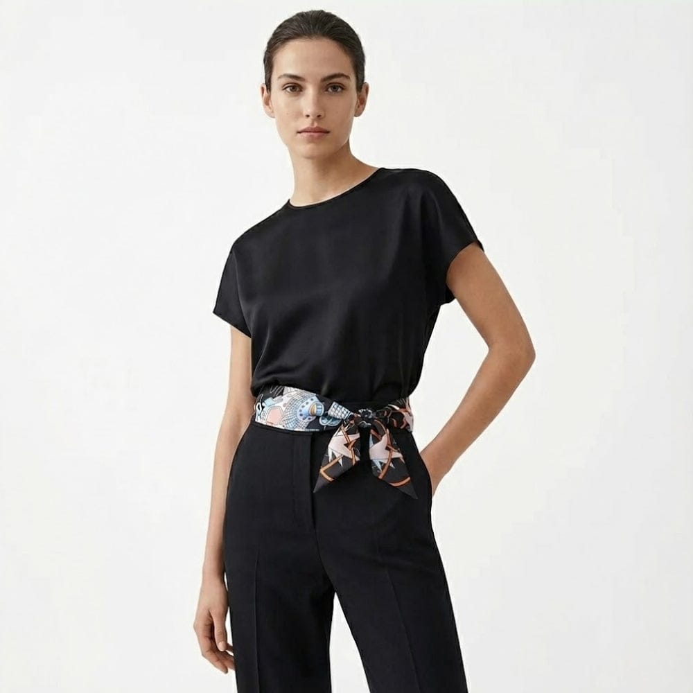 Foulard noué en satin aux motifs géométriques, porté en ceinture par une femme dans un décor minimaliste