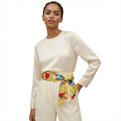 Foulard en soie jaune à motifs colorés noué en ceinture sur une tenue élégante et féminine