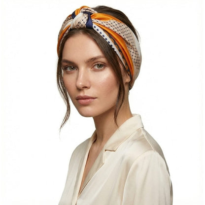 Foulard noué en satin aux motifs géométriques orange et bleu porté par une femme avec une chemise satinée