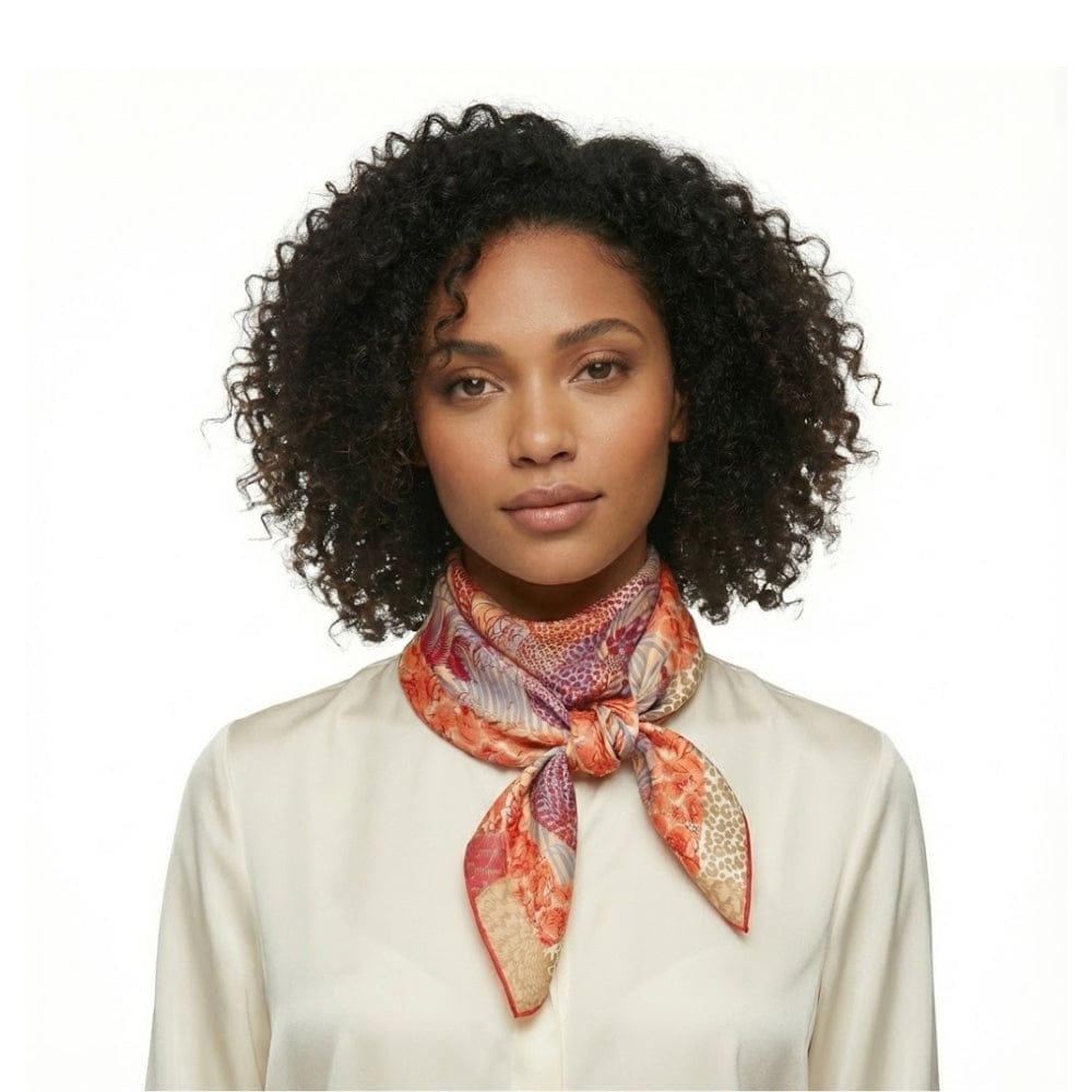 Foulard carré en satin aux motifs colorés, noué autour du cou d'une femme avec une blouse claire