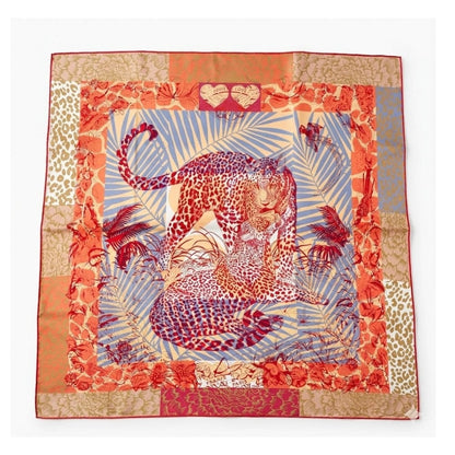 Foulard carré en satin aux motifs léopard, dominé par des teintes orange et bleue, posé sur fond blanc
