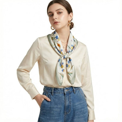 Foulard en soie noué autour du cou, avec des motifs floraux bleus et jaunes sur fond blanc, porté par un