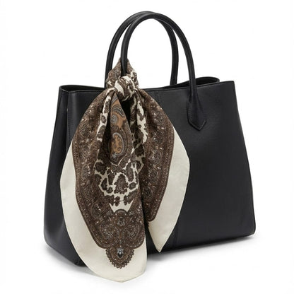Foulard en satin beige et marron noué sur un sac à main noir, motif paisley élégant pour un style affirmé