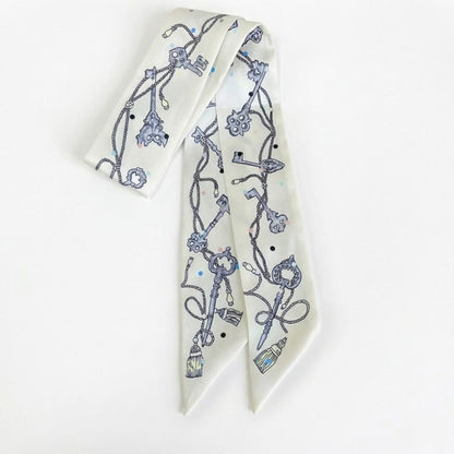 Foulard en satin blanc avec motifs de clés et cordes, forme longue et élégante, idéal pour un style bohème