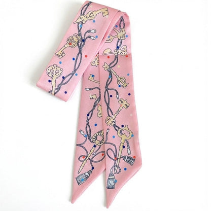 Foulard en satin rose avec motifs de clés et de points colorés, idéal pour un style bohème et raffiné