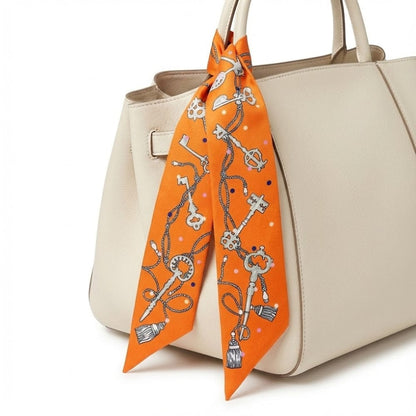 Foulard en satin orange à motifs de clés, noué sur un sac à main beige élégant