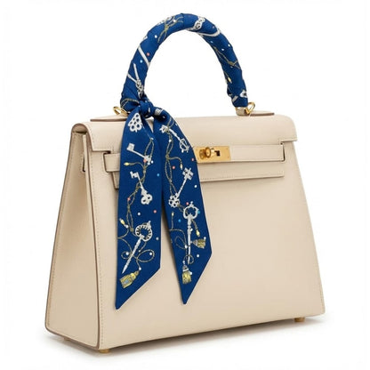 Foulard en satin bleu avec motifs dorés, noué sur le poignet d'un sac à main beige élégant