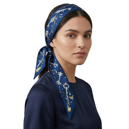 Foulard en satin bleu marine à motifs dorés, porté en bandeau sur une femme élégante