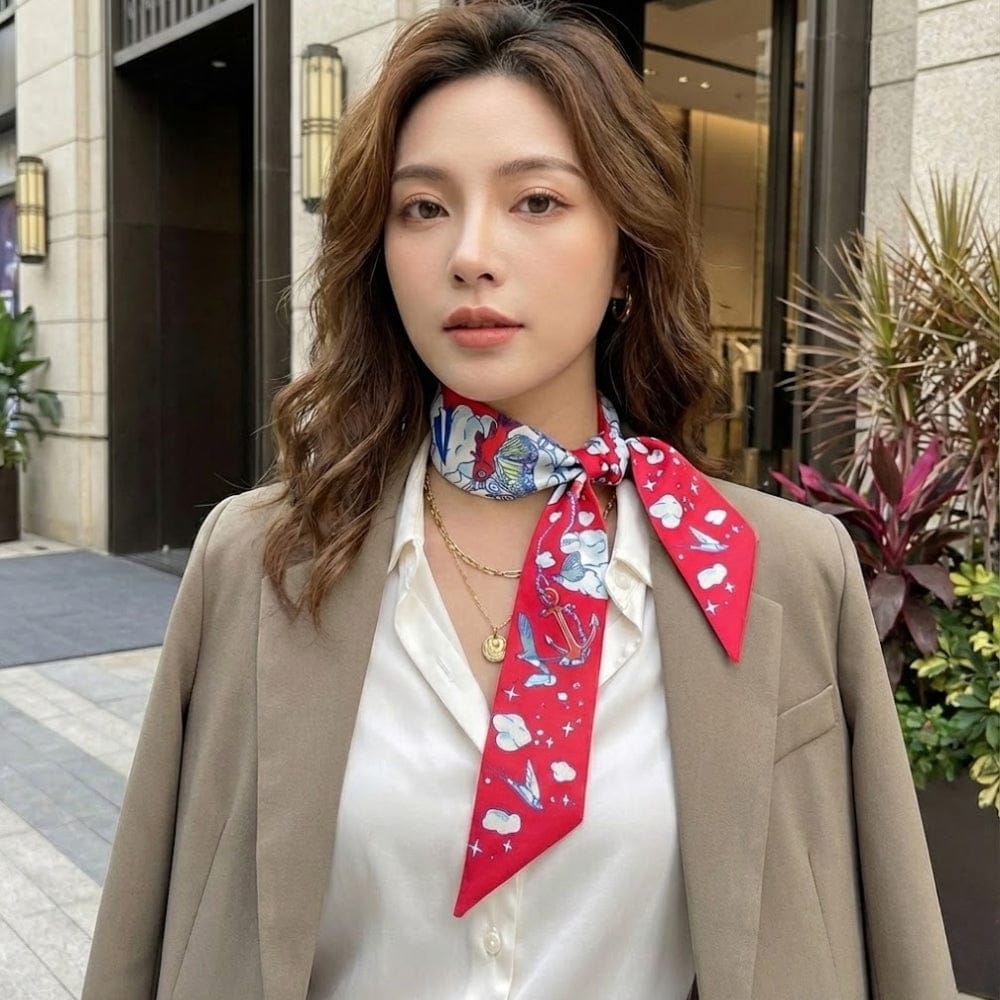 Foulard en satin rouge à motifs marins, noué autour du cou d'une femme élégante en extérieur