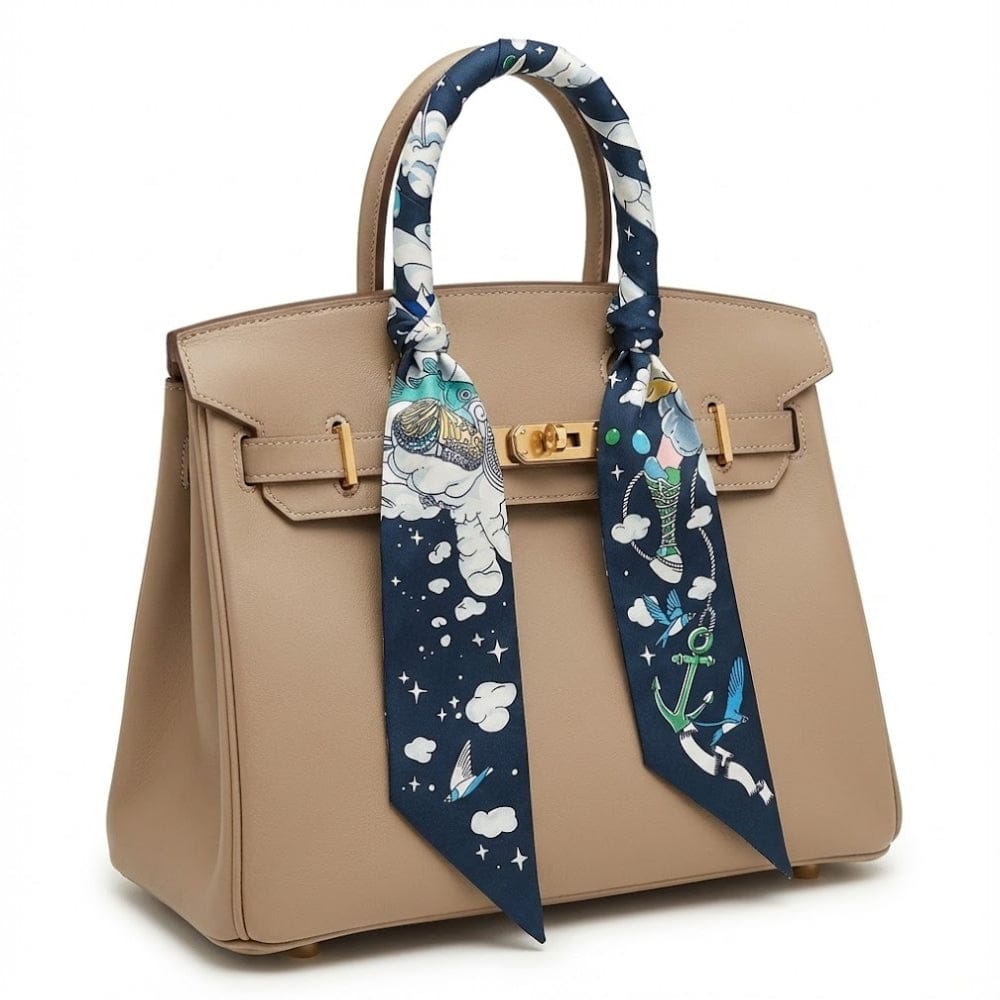 Foulard en satin bleu marine à motifs d'astronautes, noué élégamment sur un sac à main beige