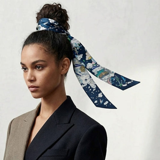 Foulard en satin bleu marine avec motifs colorés, noué en bandeau sur un chignon, porté par une femme