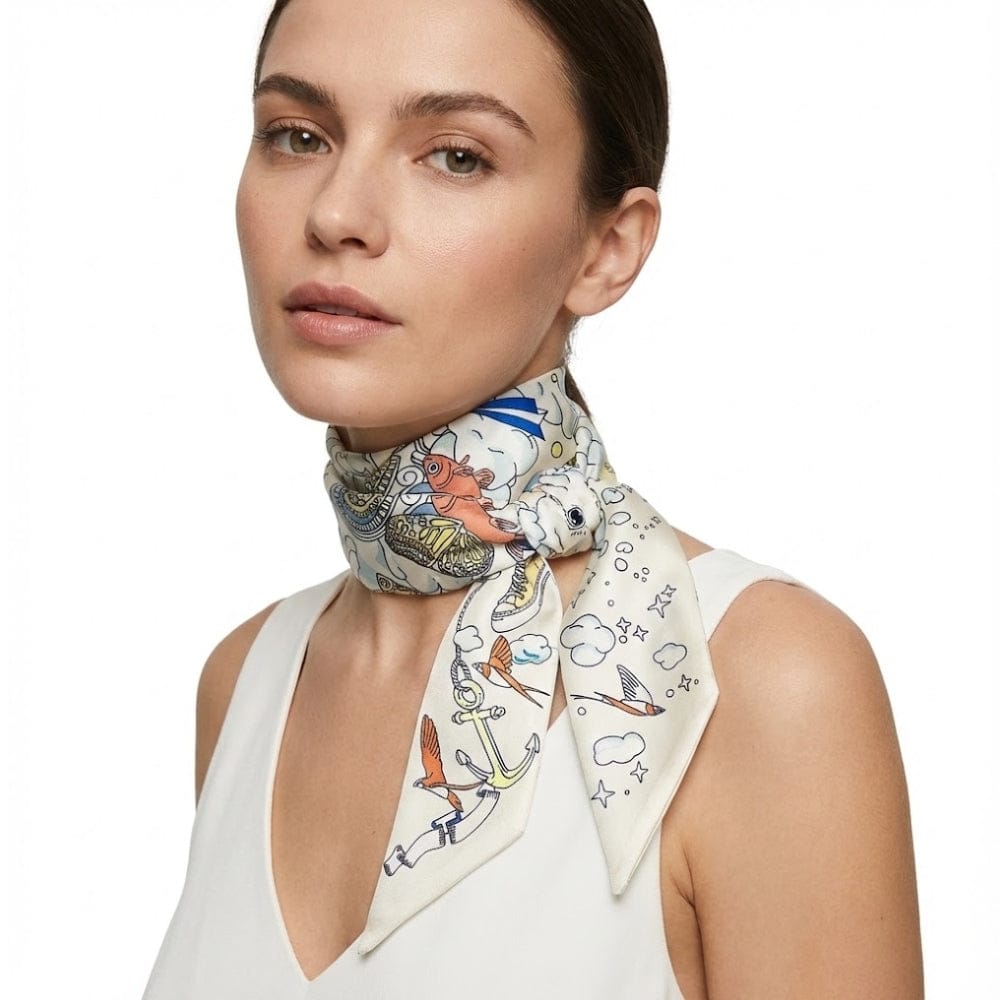Foulard en soie noué autour du cou, décoré de motifs colorés sur fond crème, porté par une femme