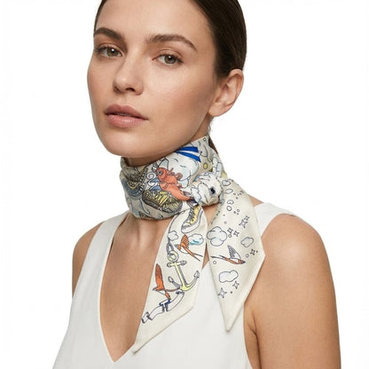 Foulard en soie noué autour du cou, décoré de motifs colorés sur fond crème, porté par une femme