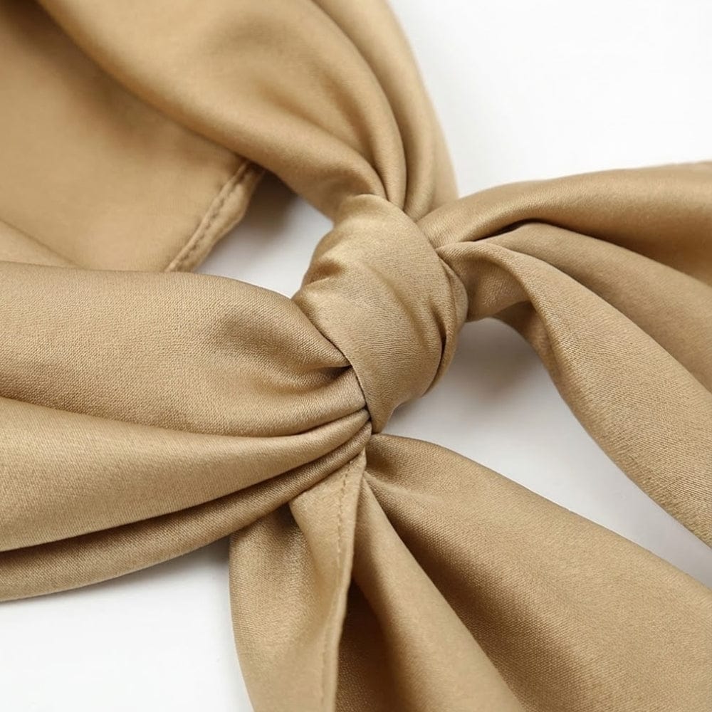 Foulard en satin beige noué, avec une texture douce et brillante, idéal pour un look élégant et sophistiqué