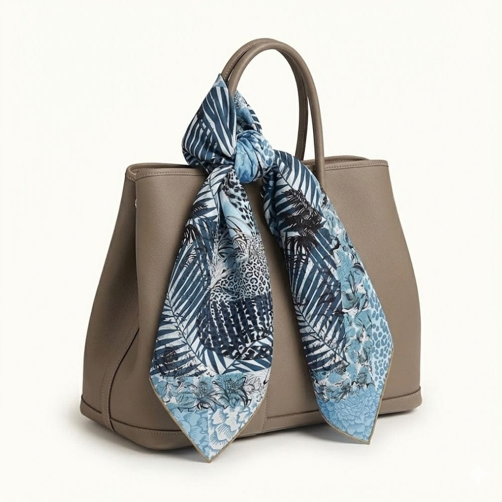 Foulard en soie bleu avec motifs léopard et feuillage, noué sur un sac à main beige élégant