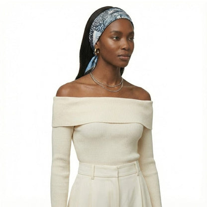 Foulard en soie bleu avec motif léopard, porté en bandeau par une femme au look sophistiqué
