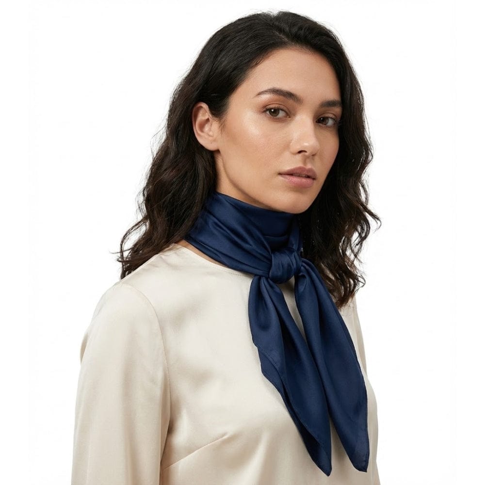 Foulard en satin bleu marine noué autour du cou d'une femme, apportant une touche d'élégance raffinée