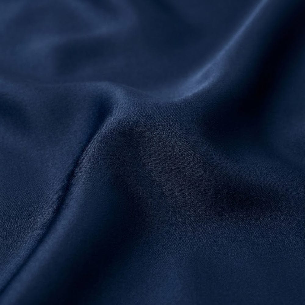 Foulard en satin bleu marine, au toucher doux et brillant, drapé élégamment sur une surface lisse