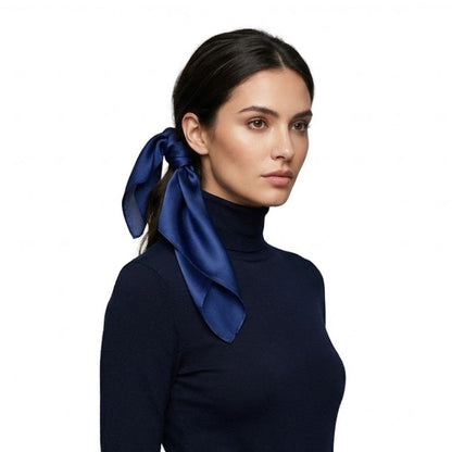 Foulard en soie bleu profond noué avec élégance dans les cheveux d'une femme portant un haut noir