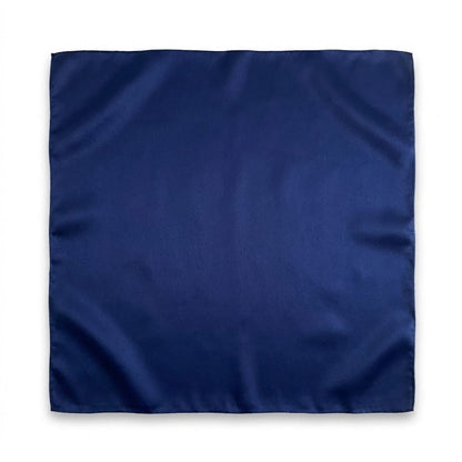 Foulard carré en soie de couleur bleu profond, au fini lisse et élégant, posé sur un fond neutre