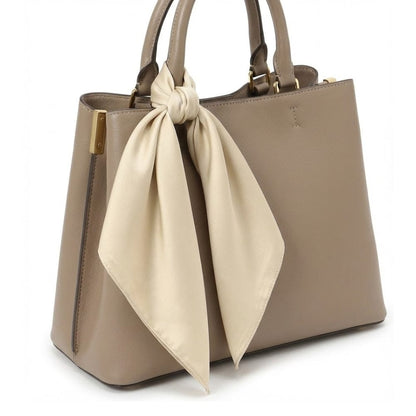 Foulard en satin beige noué sur un sac à main élégant, ajoutant une touche chic et féminine