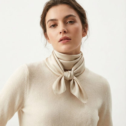 Foulard en satin beige noué autour du cou d'une femme, apportant une touche d'élégance intemporelle