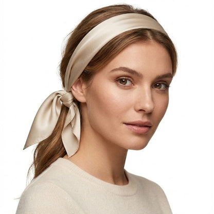 Foulard en satin beige noué sur la tête d'une femme, apportant une touche d'élégance intemporelle