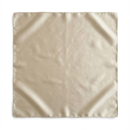 Foulard carré en soie de couleur beige, avec une texture lisse et brillante, posé sur un fond neutre