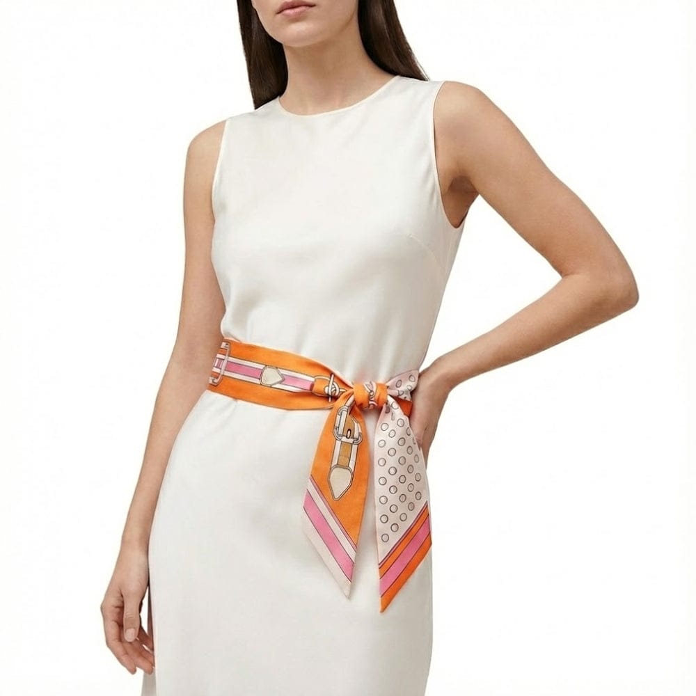 Foulard en satin orange à motifs géométriques noué en ceinture sur une robe blanche élégante