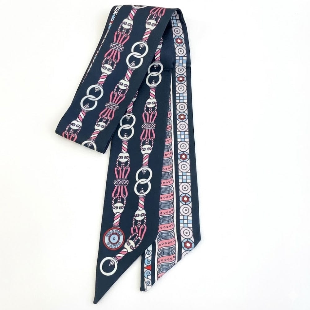 Foulard en satin bleu marine avec motifs géométriques et graphiques, noué élégamment sur une femme