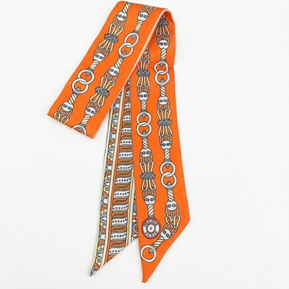 Foulard en satin orange avec motifs graphiques, noué élégamment sur une femme, ajoutant une touche moderne et féminine