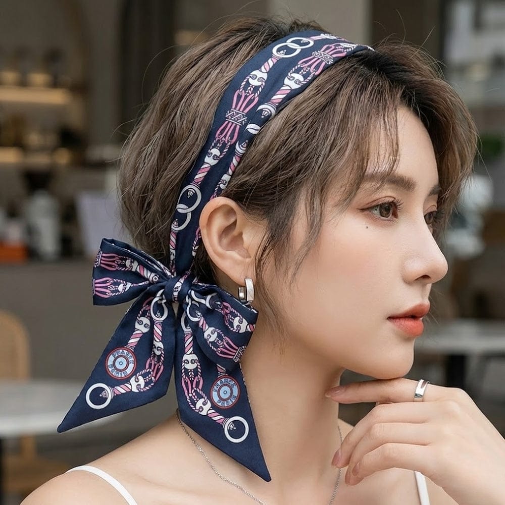 Foulard en satin bleu marine à motifs graphiques, noué élégamment autour des cheveux d'une femme au style moderne