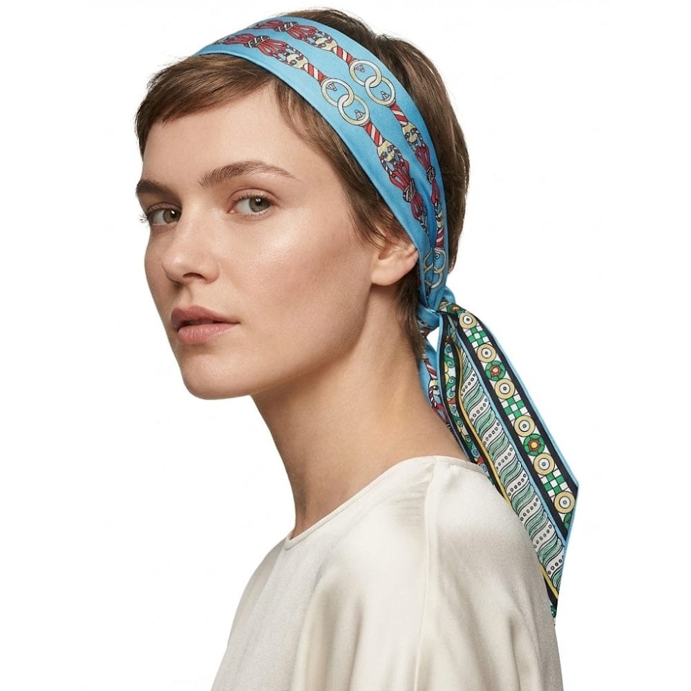 Foulard en soie bleu à motifs colorés noué sur une coiffure courte, porté par une femme élégante