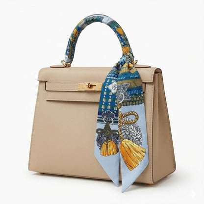 Foulard en soie noué sur un sac beige, avec des motifs colorés de bleu, jaune et vert
