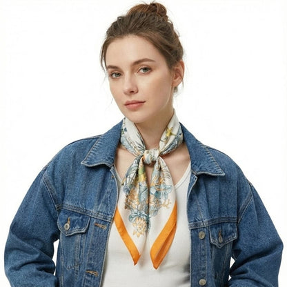 Foulard en soie aux motifs floraux bleu et orange noué autour du cou d'une femme portant une veste en jean