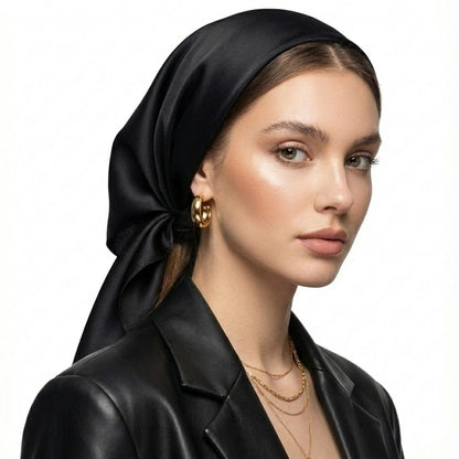 Foulard en soie noir noué élégamment sur une femme portant un blazer en cuir, avec des accessoires dorés