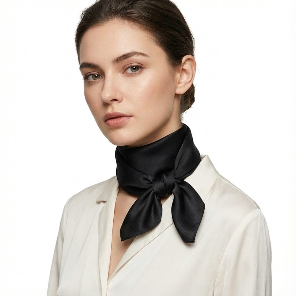 Foulard en soie noir noué autour du cou d'une femme, avec un éclat satiné sur fond blanc