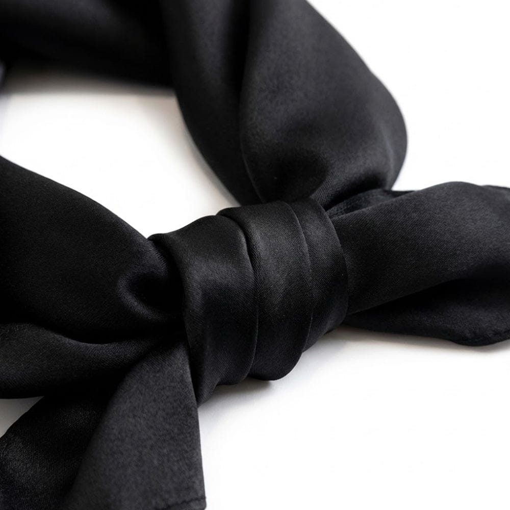 Foulard en soie noir, noué avec un élégant drapé, mettant en valeur sa texture lisse et brillante