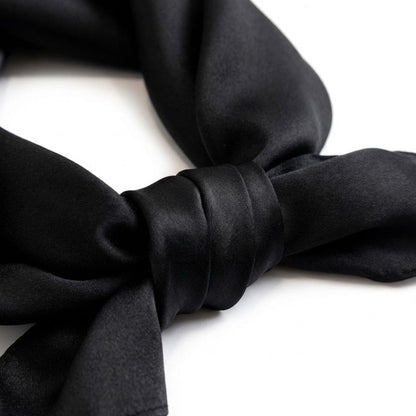 Foulard en soie noir, noué avec un élégant drapé, mettant en valeur sa texture lisse et brillante