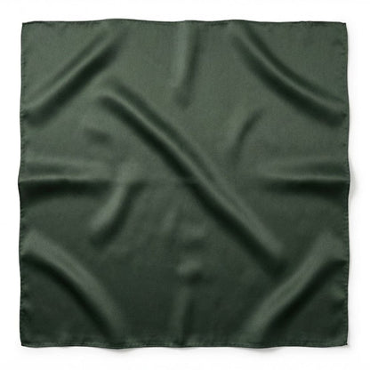 Foulard carré en soie de couleur vert foncé, au fini lisse et brillant, posé sur une surface blanche