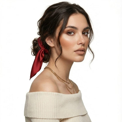 Foulard en soie rouge noué dans les cheveux d'une femme, ajoutant une touche sophistiquée à son look